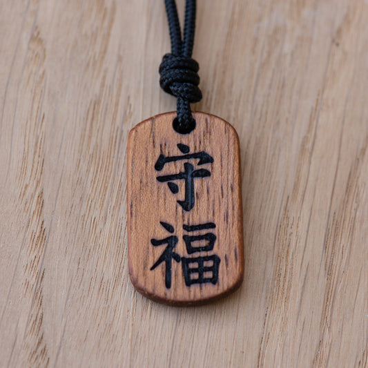 Close up of Mamoru and Fuku kanji engraving on solid Iroko wood pendant