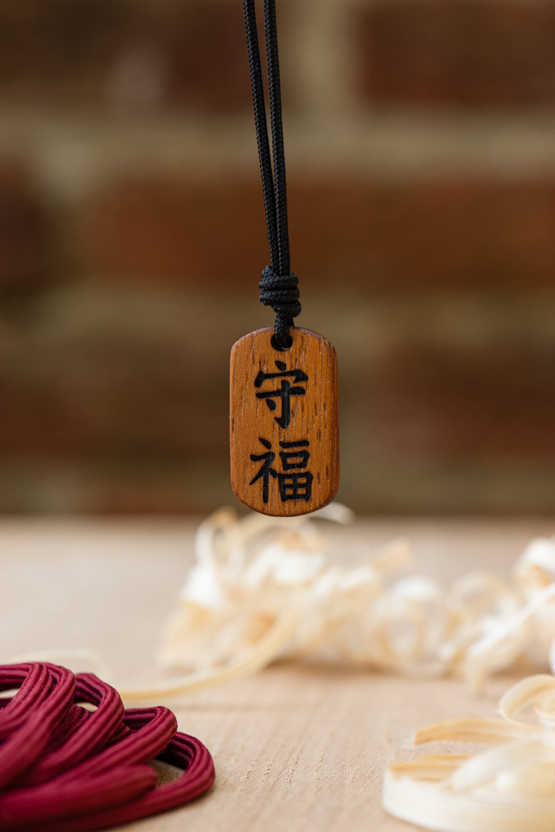 Japanese protection talisman pendant in Iroko wood with natural grain texture